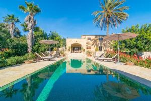 a pool with chairs and umbrellas in front of a house at Finca Son Punta in Felanitx