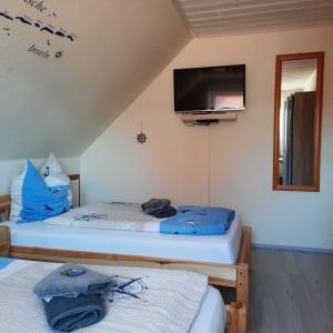 two beds in a room with a tv on the wall at Gästehaus Mia in Norddeich