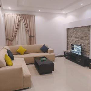 sala de estar con sofá y TV en Evan Suites Serviced Apartments, en Riad