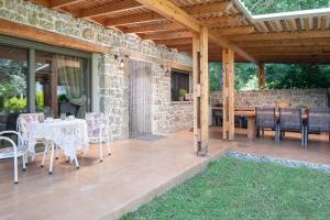 un patio con mesa, sillas y pared de piedra. en Villa Menie - Golden Fig Sykia lodge, en Paralia Sikias