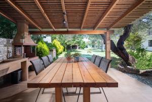 Paralia Sikias的住宿－Villa Menie - Golden Fig Sykia lodge，木制凉棚下的木桌和椅子