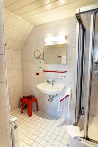 a white bathroom with a sink and a red stool at Garni Hotel Maselheimer Hof in Maselheim
