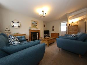 a living room with blue couches and a tv at 16 Westgate South in Anstruther