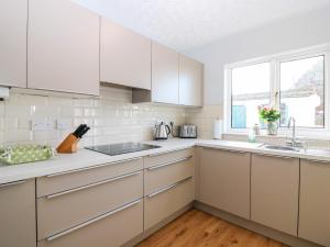 a white kitchen with white cabinets and a window at 16 Westgate South in Anstruther