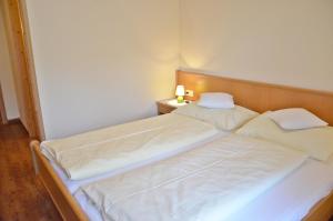 a bedroom with two beds with white sheets and a lamp at Hoferbauergut in Strobl