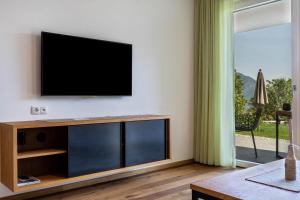sala de estar con TV de pantalla plana en la pared en Pataunerhof Tilia Lodge, en Tirolo