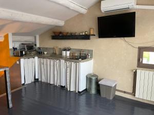 una cucina con bar con tende bianche e TV di La Maison de Sofia a Vallabrix