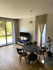 a living room with a table and chairs and a tv at Bella luna vila Palanga with forest view in Palanga