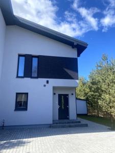 una casa blanca con una puerta negra y un cielo en Bella luna vila Palanga with forest view, en Palanga