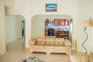 a living room with a couch and a kitchen at CARNATION 156 in Montego Bay