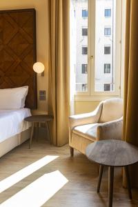 a bedroom with a bed and a chair and a window at Hotel Dei Dragomanni in Venice