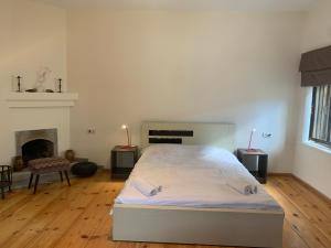 a white bedroom with a bed and a fireplace at Hotel Lemi in Mestia