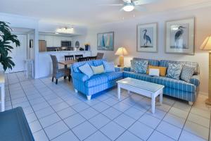 uma sala de estar com sofás azuis e uma mesa em COQUINA 3C em Sanibel
