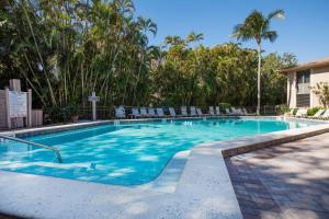 Una gran piscina con sillas y árboles. en Coquina Beach 3C, en Sanibel