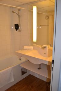 uma casa de banho com um lavatório, uma banheira e um espelho. em Lenas West Hotel em Viena