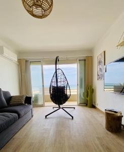 een woonkamer met een mandstoel voor een raam bij "EDEN" Exceptionnel! Vue mer 10m de la plage parking privé gratuit à 100m in Canet-en-Roussillon