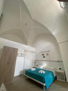 レヴェラーノにあるB&B Cadornaの白い部屋に青いベッドが備わるベッドルーム1室