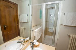 y baño blanco con lavabo y ducha. en Hotel Reyes Catolicos, en Salamanca