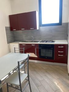 cocina con fogones, fregadero y mesa en B&B Cadorna, en Leverano