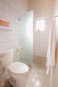 baño blanco con aseo y ventana en Topia Retreat - Piscina Suite Norte, en El Pescadero