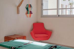 una silla roja en una habitación con ventana en Topia Retreat - Piscina Suite Norte, en El Pescadero