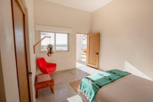 1 dormitorio con 1 cama y 1 silla roja en Topia Retreat - Piscina Suite Norte, en El Pescadero