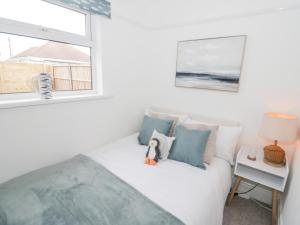 a bedroom with a white bed and a window at Cove House in Rhyl