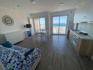 a living room with a bed and a kitchen with the ocean at Fronte mare in Polignano a Mare