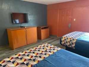 a room with two beds and a cabinet and a tv at Economy Inn Hot Springs in Hot Springs +5 photos
