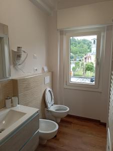 a bathroom with a toilet and a sink and a window at EderaRooms in Cerano d'Intelvi