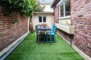 een kleine achtertuin met een tafel en stoelen op het gras bij L'harmonie in Amiens