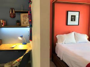 a bedroom with an orange wall and a bed and a desk at Azul Cielo Hostel in Oaxaca City