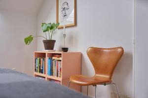 a brown chair sitting next to a book shelf at Penthouse Cph inner city in Copenhagen