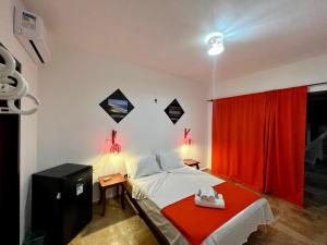 a bedroom with a bed with a red curtain at Pousada Califórnia Tia Lia in Paracuru