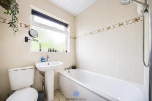 a bathroom with a tub and a toilet and a sink at Coventry Large Stylish 4 Bedroom House, Sleeps 8, Private Parking, by EMPOWER HOMES in Coventry