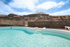 a large swimming pool with a rock wall at Playa Marina Eco Bungalow Mala in Arrieta