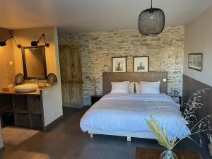 a bedroom with a bed and a stone wall at La Maison de Sofia in Vallabrix