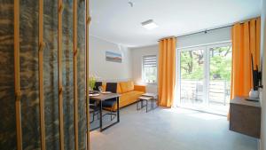 a living room with an orange couch and a table at Apartamenty EverySky - Nad Łomnicą 1E-2B in Karpacz