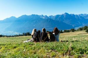 three women sitting on a hill looking at the mountains at Kristemoarhütte in Gaimberg