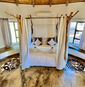 a bed with a canopy in a room with windows at Gamagara Africa Private Nature Reserve in Kathu