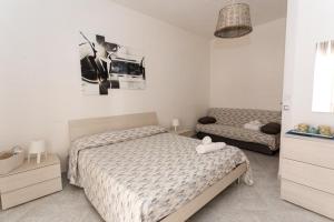 a white bedroom with a bed and a chair at B&B La Barcaccia in Tortora