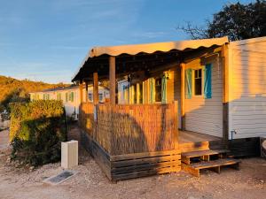 uma pequena casa com um alpendre e um deque de madeira em Joli Mobil-Home de Vacances, Ideal pour les familles em Rocbaron