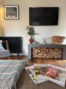 a living room with a tv and a table with a newspaper at Cuckoostone Barn in Buxton