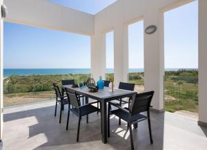 een eetkamer met een tafel en stoelen en de oceaan bij Oliva Suites in Oliva