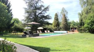 un patio con piscina con sillas y sombrilla en Le pigeonnier de la Farge, en Chaumont-sur-Tharonne