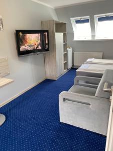 a room with two beds and a tv on the wall at Gościniec BEATA in Łagów