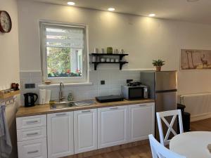 eine Küche mit weißen Schränken, Spüle und Kühlschrank in der Unterkunft Apartman Mr Guest Krapina - SELF CHECK IN in Krapina