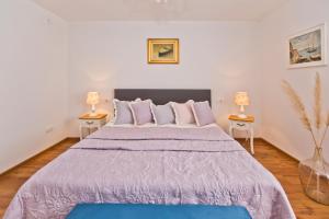 una camera con un grande letto viola con due lampade di Villa Kate -with private pool and BBQ a Brusje Altre 31 foto