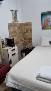 um quarto com uma cama branca e uma parede de tijolos em La Casetta na Nazaré