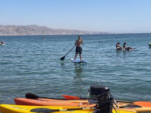 a man standing on a paddle board in the water at Presidential Penthouse in Eilat